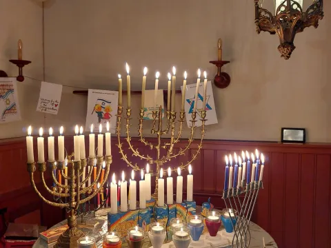 Tafel vol brandende chanoekia's, van oud en traditioneel tot modern, in de Dijksynagoge