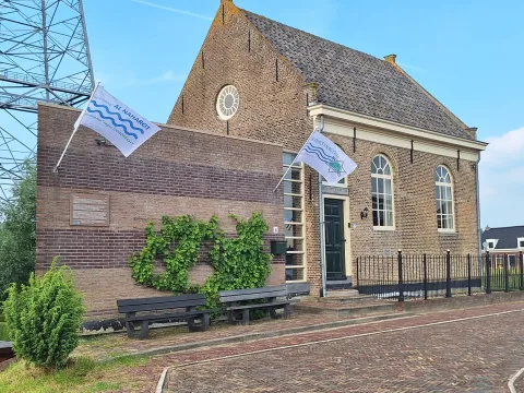De Dijksynagoge in Sliedrecht van buiten, met aan de gevel de vlaggen van Al Naharot en de Dijksynagoge