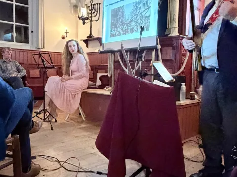 Flip de Liema met gitaar op de voorgrond, op de achtergrond zangeres Orsaya en een scherm over New York aan het begin van de twintigste eeuw