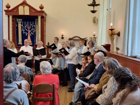 Publiek in een volle Dijksynagoge luistert naar het koor Al Naharot voor de Heilige Ark