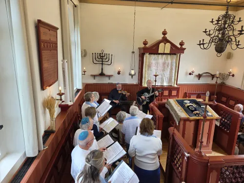 Bezoekers luisteren en zingen mee met het optreden van Al Naharot in de Dijksynagoge
